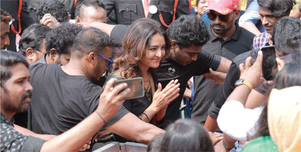 A woman is enveloped by a diverse group of people at a crowded event, highlighting the lively social interaction.